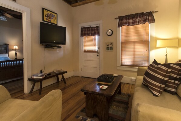 A living room with a television, a couch, a coffee table, and a door with windows.