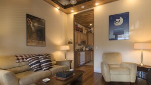 A living room with a sofa, armchair, coffee table, and a bookshelf. - Toy Box Suite at the Calhoun House Inn & Suites (Bryson City)