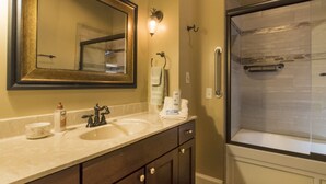 Une salle de bain avec un grand miroir, deux lavabos, une douche et un porte-serviettes.