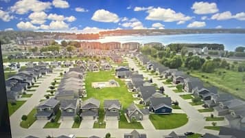 A residential area with houses arranged in rows, a central green space, and a body of water in the background.