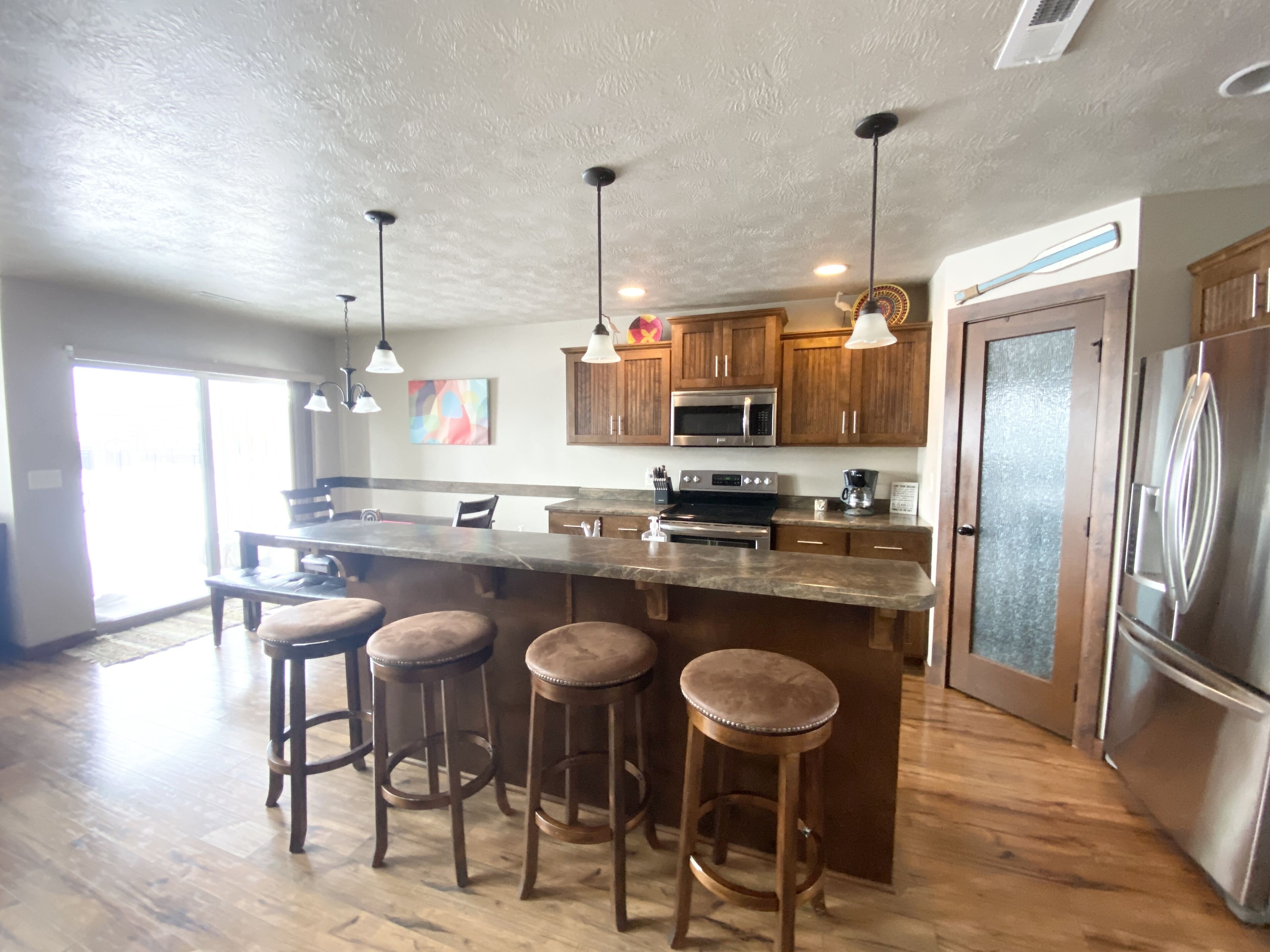 A modern kitchen with a central island, stainless steel appliances, and wooden bar stools.