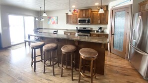 A modern kitchen with a central island, stainless steel appliances, and wooden bar stools.