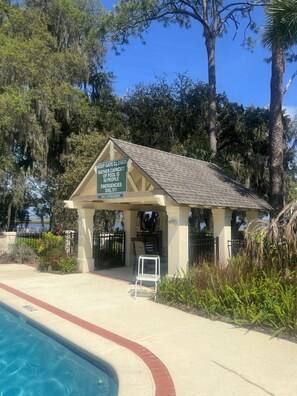 A pool area with a lifeguard station, a closed gate, and a sign indicating a 50-person capacity and emergency contact number. - Private and quiet condo on North end of SSI. 30 day minimum. 
 (St. Simons Island)