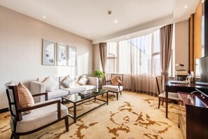Una sala de estar moderna con un juego de sofá, una mesa de centro y un televisor. Hay cortinas en las ventanas y una planta en el alféizar.