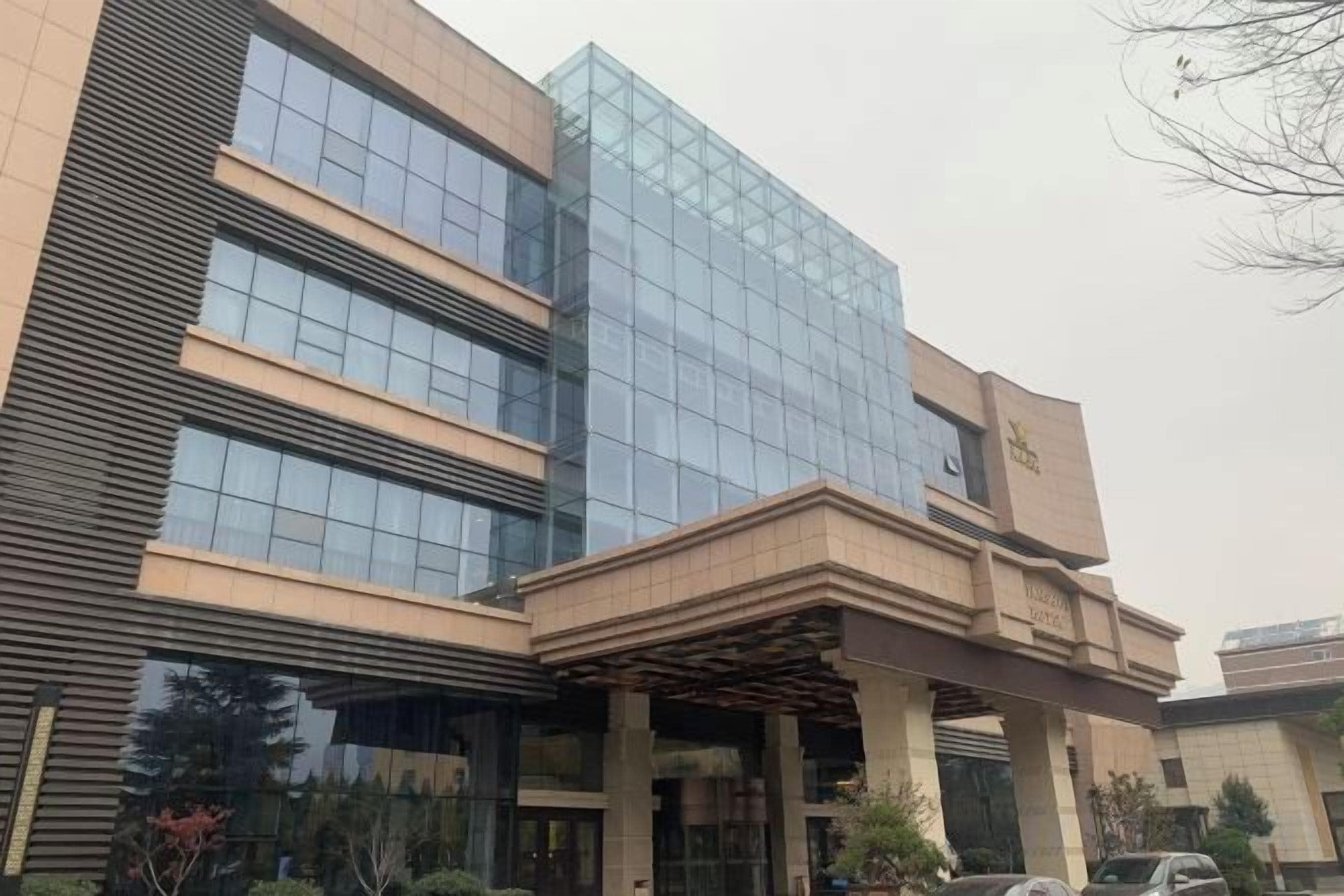 A modern building with a glass facade and a covered entrance area.