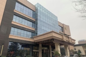 A modern building with a glass facade and a covered entrance area.