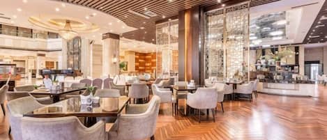 Un amplio vestíbulo de hotel con piso de madera, varias zonas de estar y un bar central.