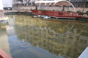 Un étang avec un pont et une structure circulaire au milieu de l’eau.