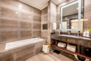 A modern bathroom with a large bathtub, a vanity with a mirror, and a towel rack. - Tianshui Hotel (Tianshui)