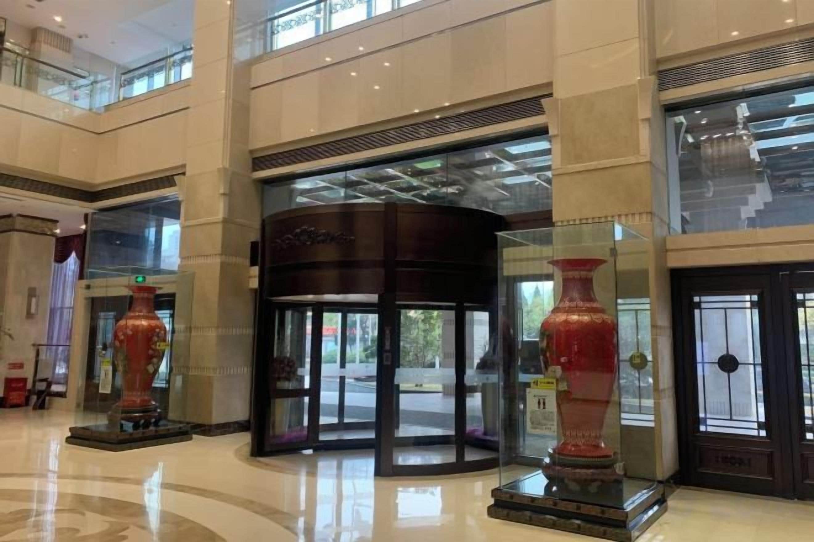 A hotel lobby with a revolving door, large vases, and a glass entrance.