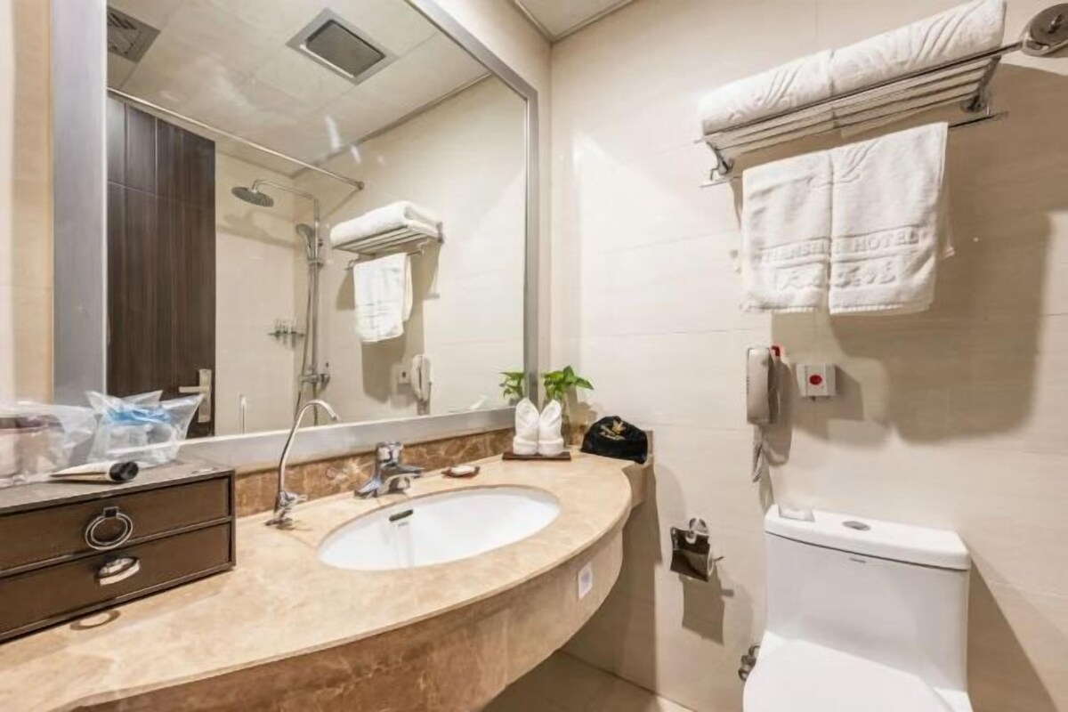 Un baño con lavamanos, espejo, toallero y retrete.