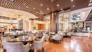 Un amplio vestíbulo de hotel con piso de madera, varias zonas de estar y un bar central.
