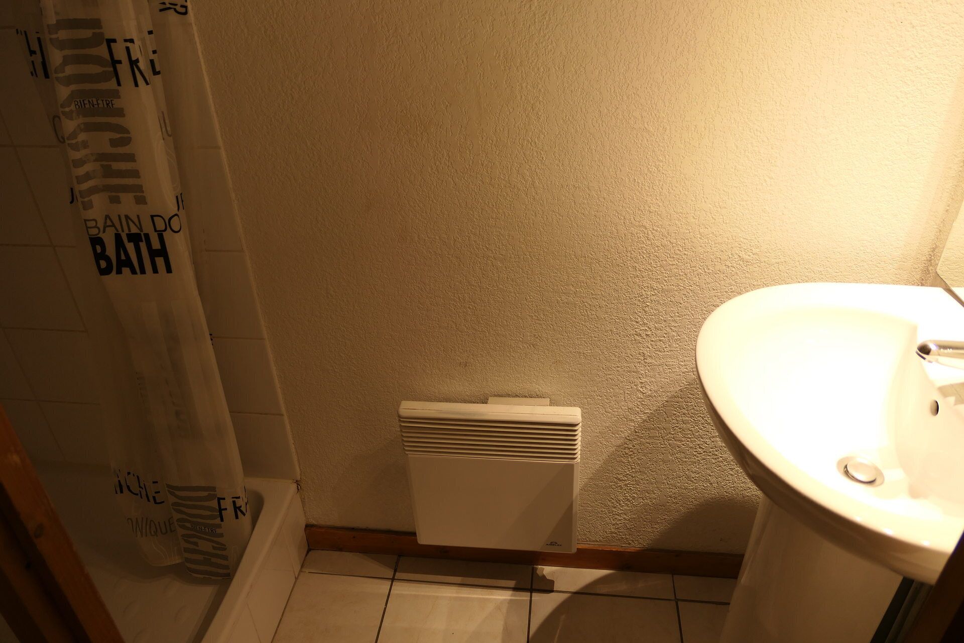 Ein Badezimmer mit einem weißen Waschbecken, einer Duschvorhang mit Text und einem weißen Heizkörper.
