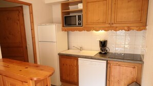 Eine Küche mit Holzausstattung, einem weißen Kühlschrank, einer Mikrowelle, einer Kaffeemaschine und einem Geschirrspüler.