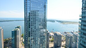 A high-rise building with a glass facade overlooking a body of water and other buildings. - Downtown Toronto near CN Tower (Toronto)