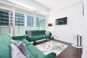 Una sala de estar moderna con un sofá verde, un tapete estampado y un televisor de pantalla plana montado en la pared.
