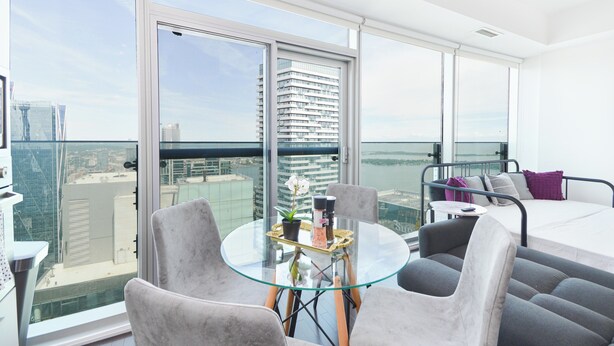 A modern balcony with a glass table, grey and black furniture, and a city view. - Downtown Toronto near CN Tower (Toronto)