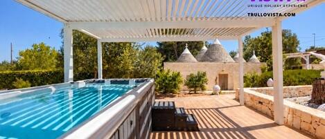 Relax under the pergola beside the spa with charming trulli views
