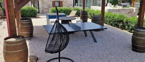 Shaded outdoor ping pong area with rustic charm and relaxing courtyard vibes