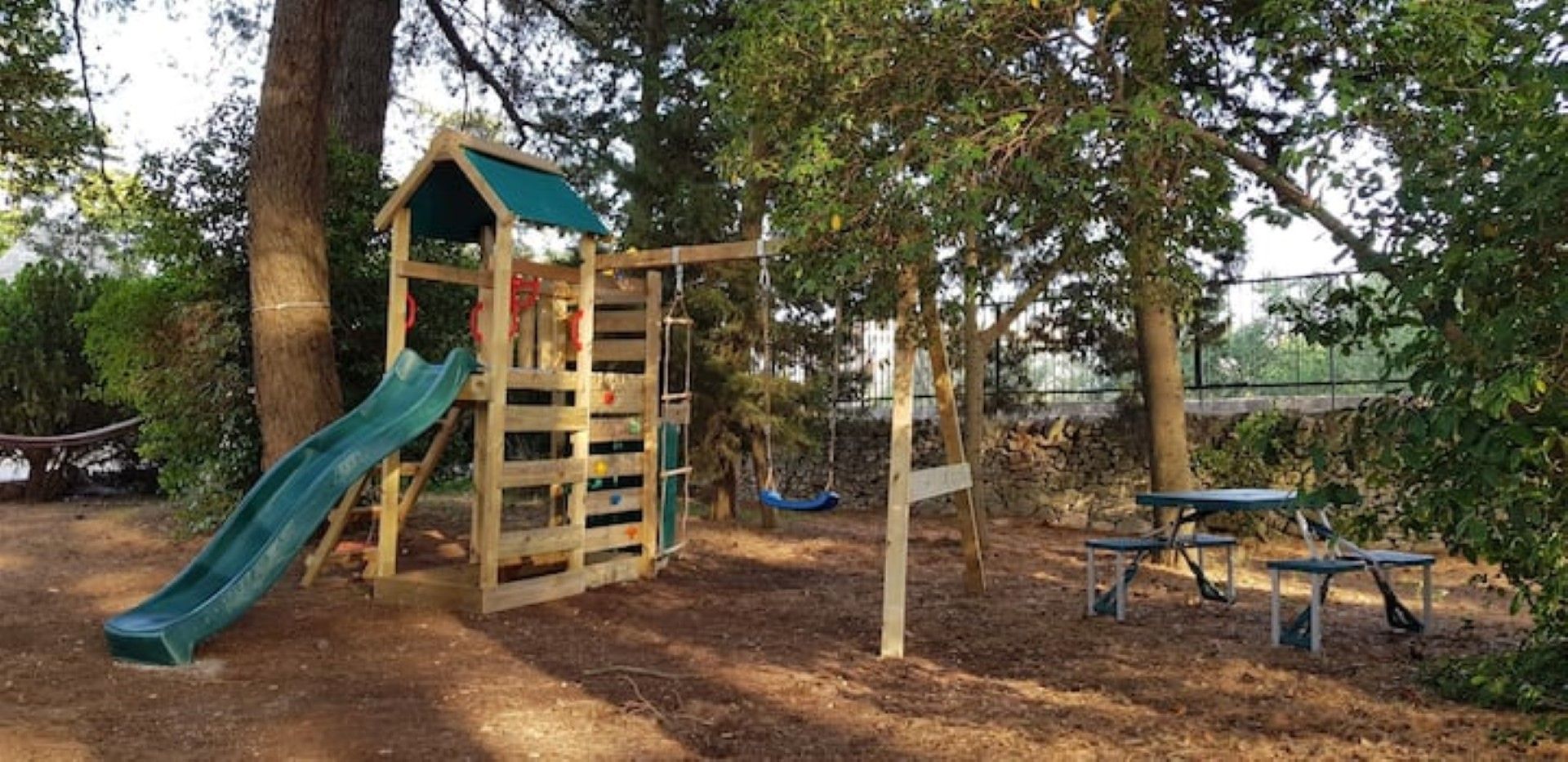 Ein Spielplatz mit Rutsche, Schaukeln und einer kleinen Schutzhütte.