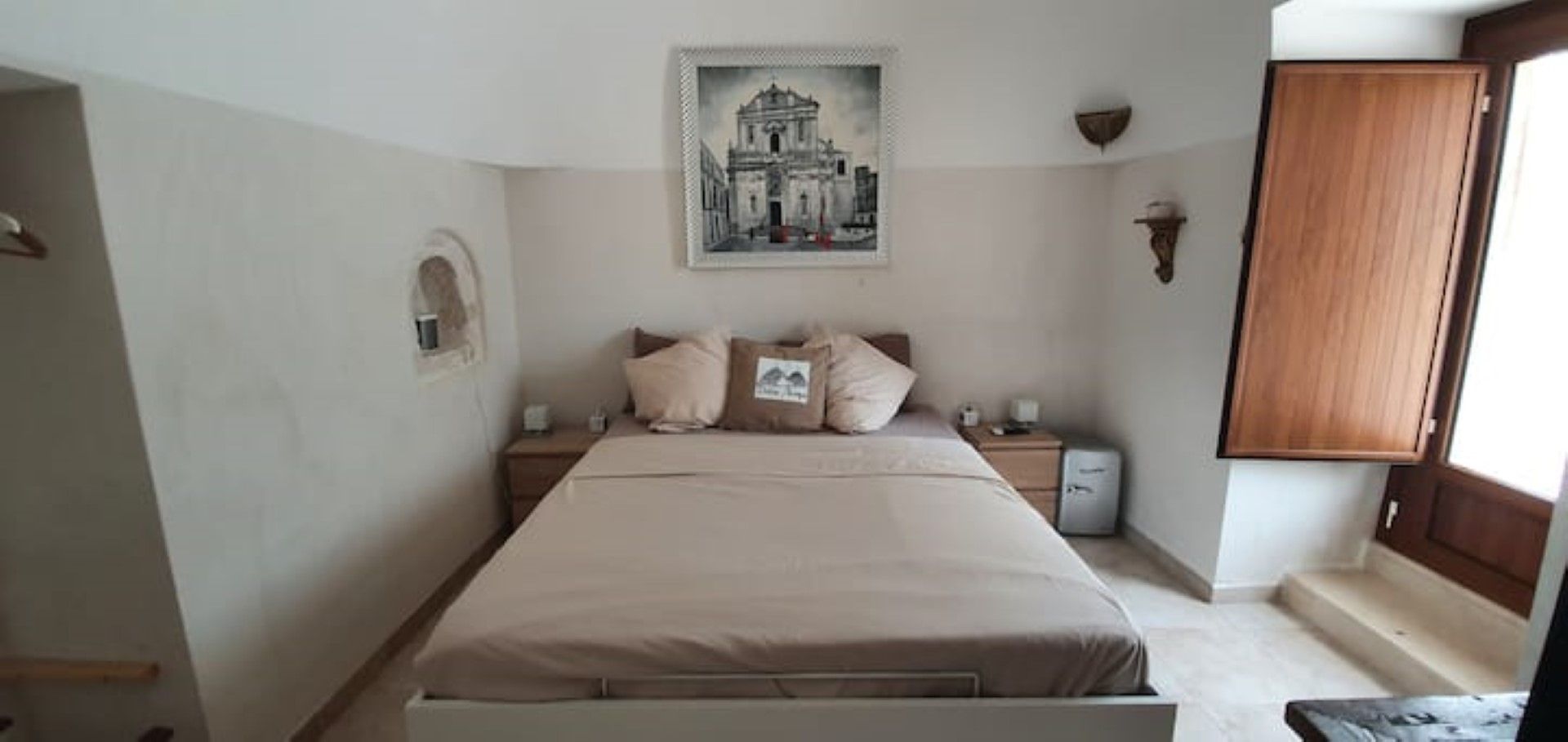 Ein Schlafzimmer mit einem Bett, einem Nachttisch, einer Wandablage und einer Tür.