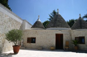 A stone building with three conical roofs, a wooden door, and potted plants.