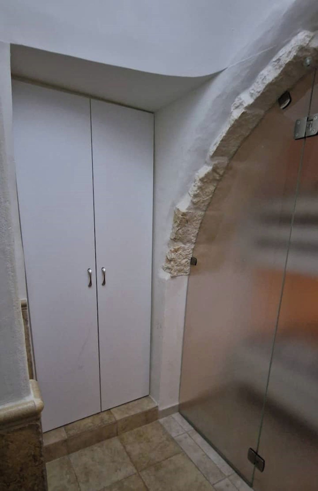 Een kamer met een witte inloopkast, een glazen deur en een stenen muur.