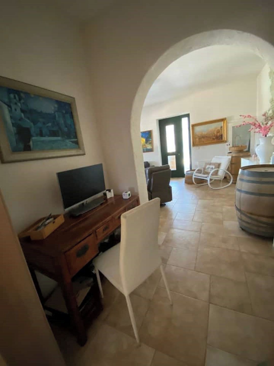 Un salon avec un téléviseur, un bureau et une chaise. Une porte donne accès à une autre pièce.