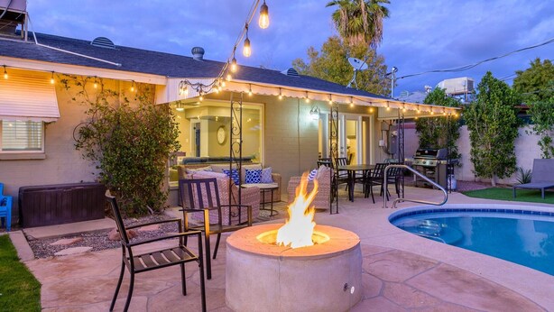 An outdoor patio area with a fire pit, seating, and a pool. - Old Town 4BR Gem | Pool, Firepit, WiFi, & Games! (Scottsdale)
