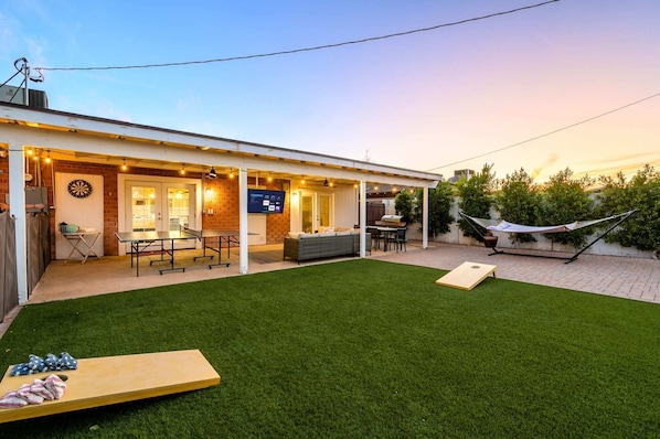 A covered patio area with a dartboard, ping pong table, and seating.
