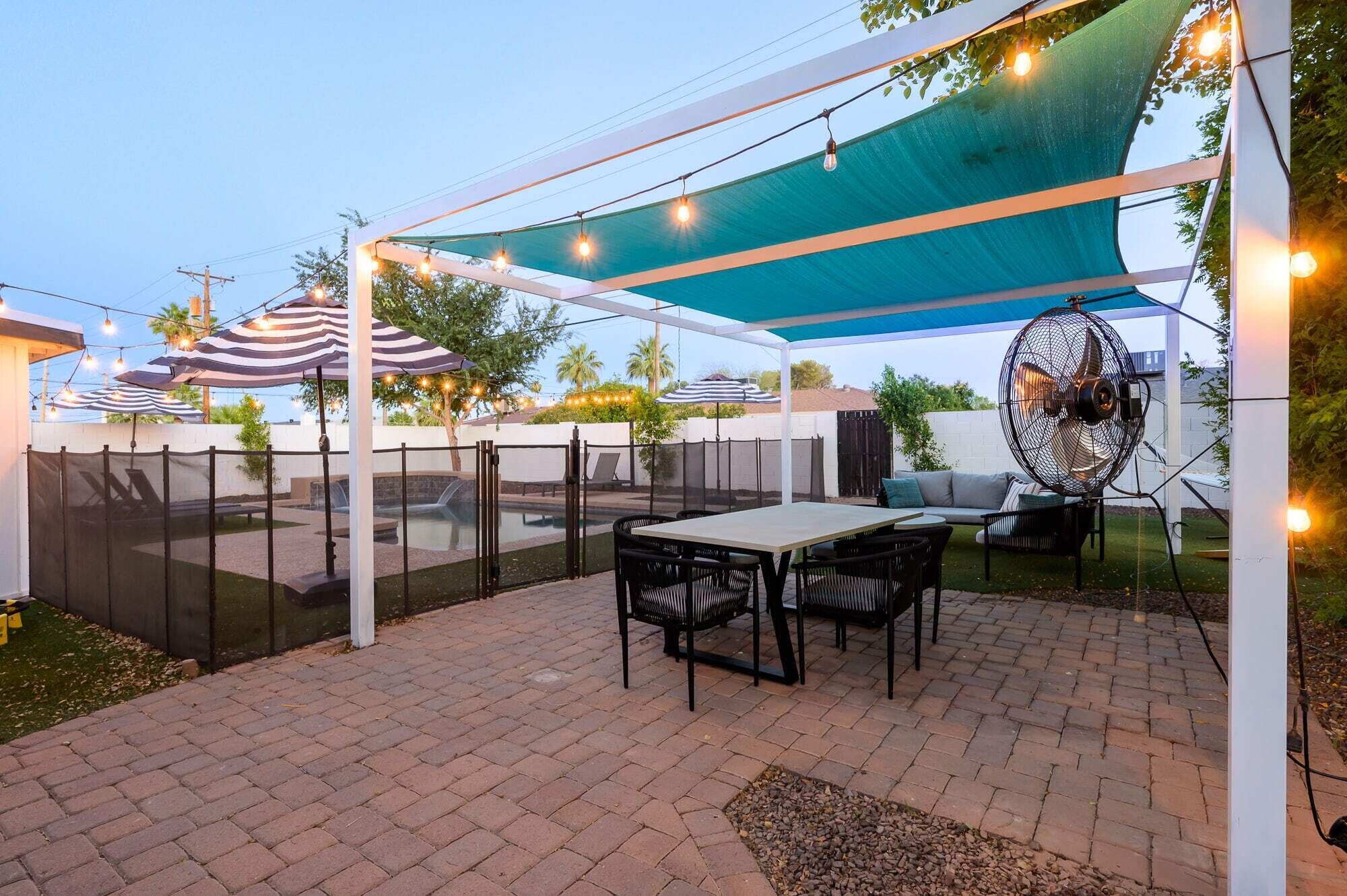 Eine Terrasse im Freien mit Tisch und Stühlen, einem Pool und Lichterketten.