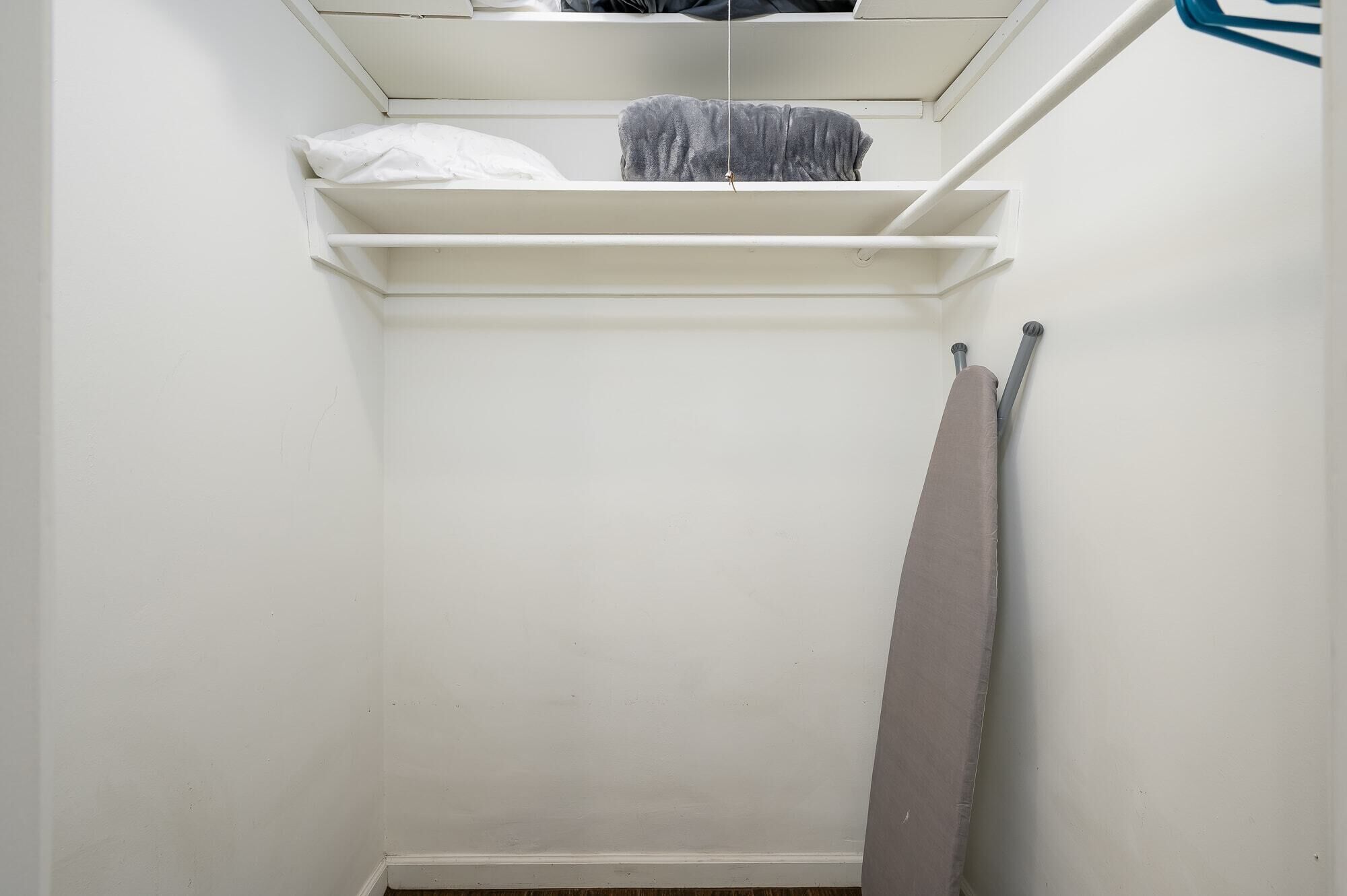 Een witte kast met planken en kledingroede.