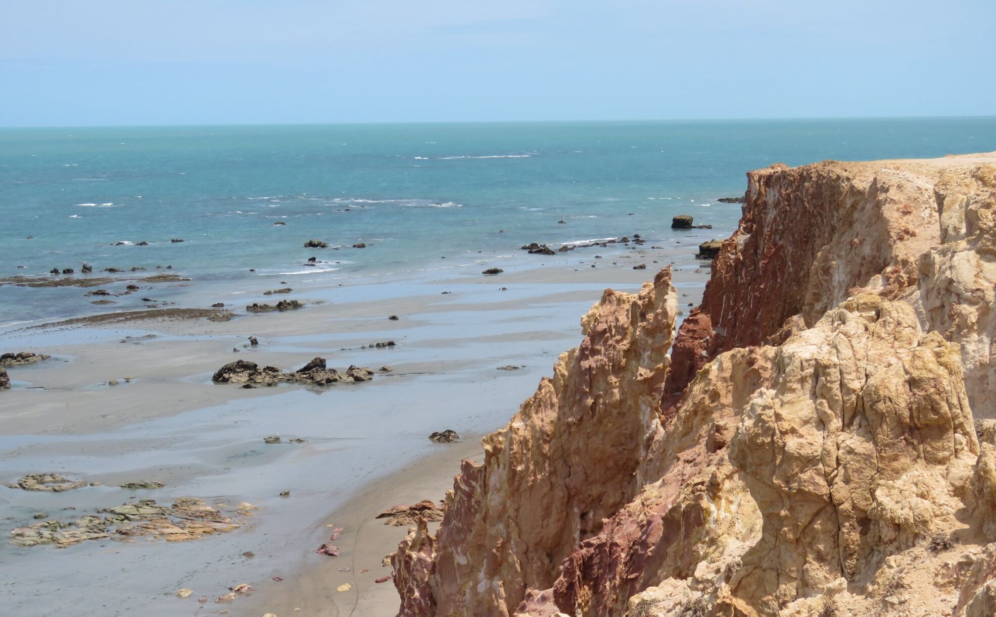 Un paisaje costero con un acantilado rocoso y una playa arenosa.
