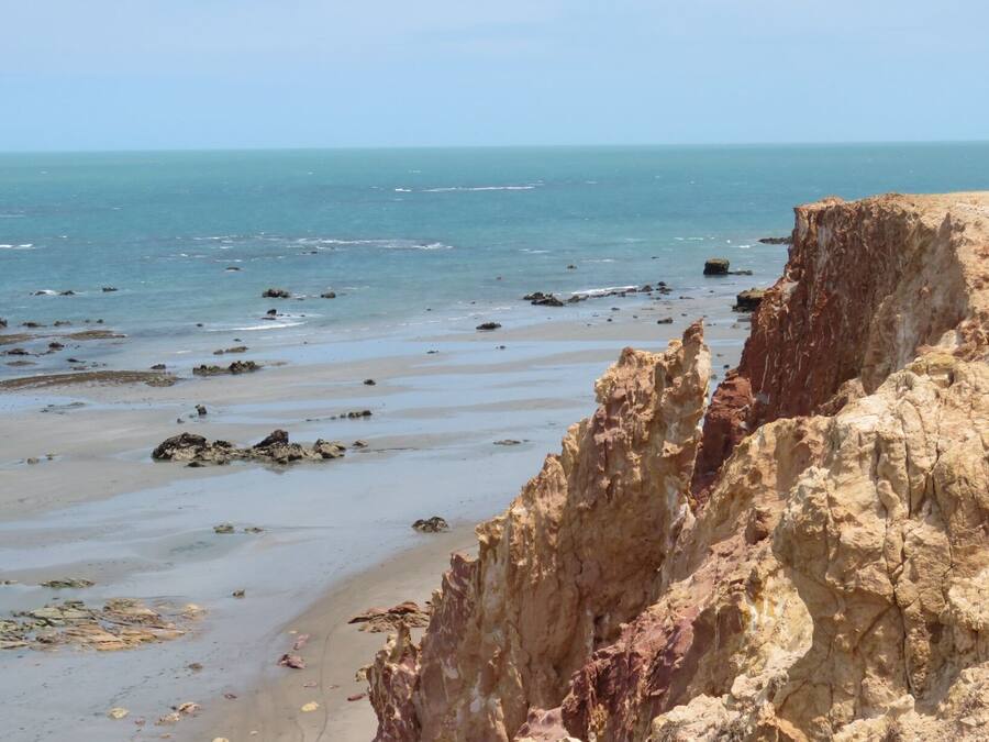 Un paisaje costero con un acantilado rocoso y una playa arenosa.