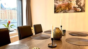 A dining area with a wooden table, black chairs, a vase, candles, and a framed picture of a lynx. - App. 5 - wohlB2 (3 Zi, 2 adult + 2 kids) (Braunlage)