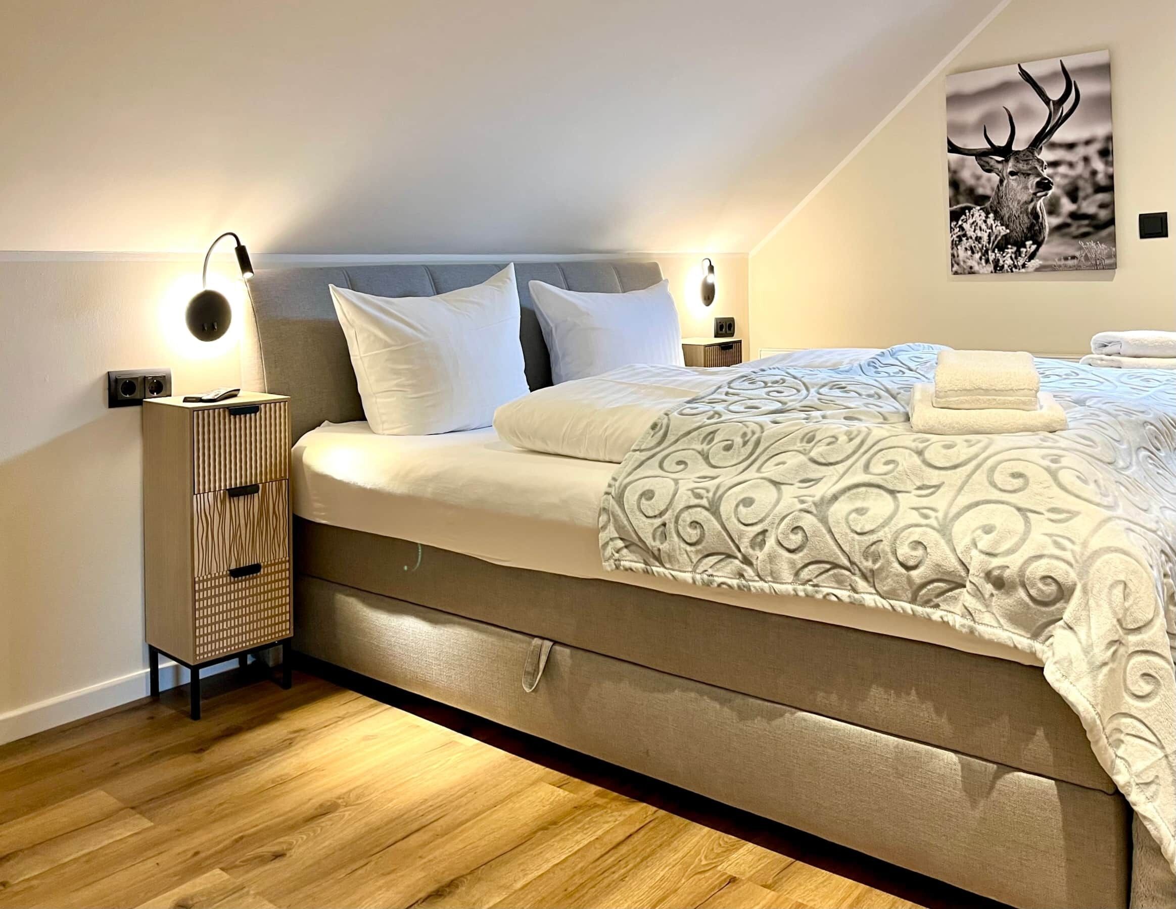 Une chambre à coucher moderne avec un lit, deux lampes de chevet, une table de chevet et un tableau accroché au mur.