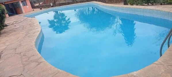 A swimming pool with a tiled edge, surrounded by a stone deck. - Kibwezi greenpark (Kibwezi)