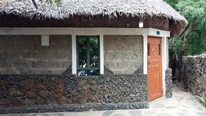 Un edificio rústico con techo de paja, pared de piedra y puerta de madera.