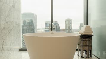 Une salle de bain moderne avec une baignoire îlot, une fenêtre encadrée de verre et un banc décoratif recouvert de carreaux.