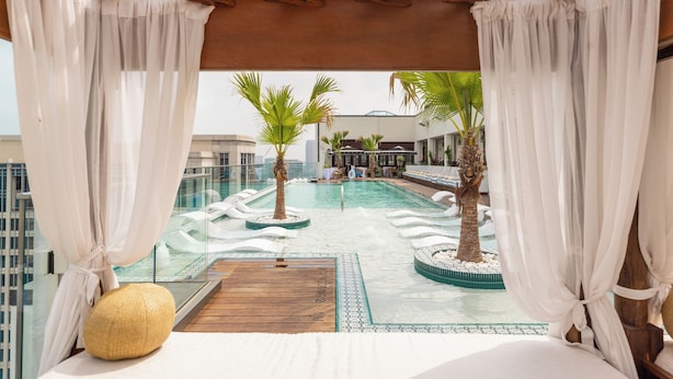 A rooftop pool area with a wooden deck, palm trees, and a view of the cityscape. - Hôtel Swexan (Dallas)