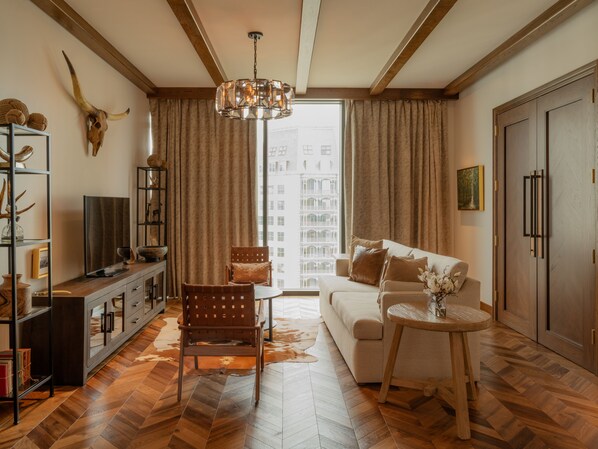 A modern living room with a sofa, a wooden coffee table, a TV, and a bookshelf.