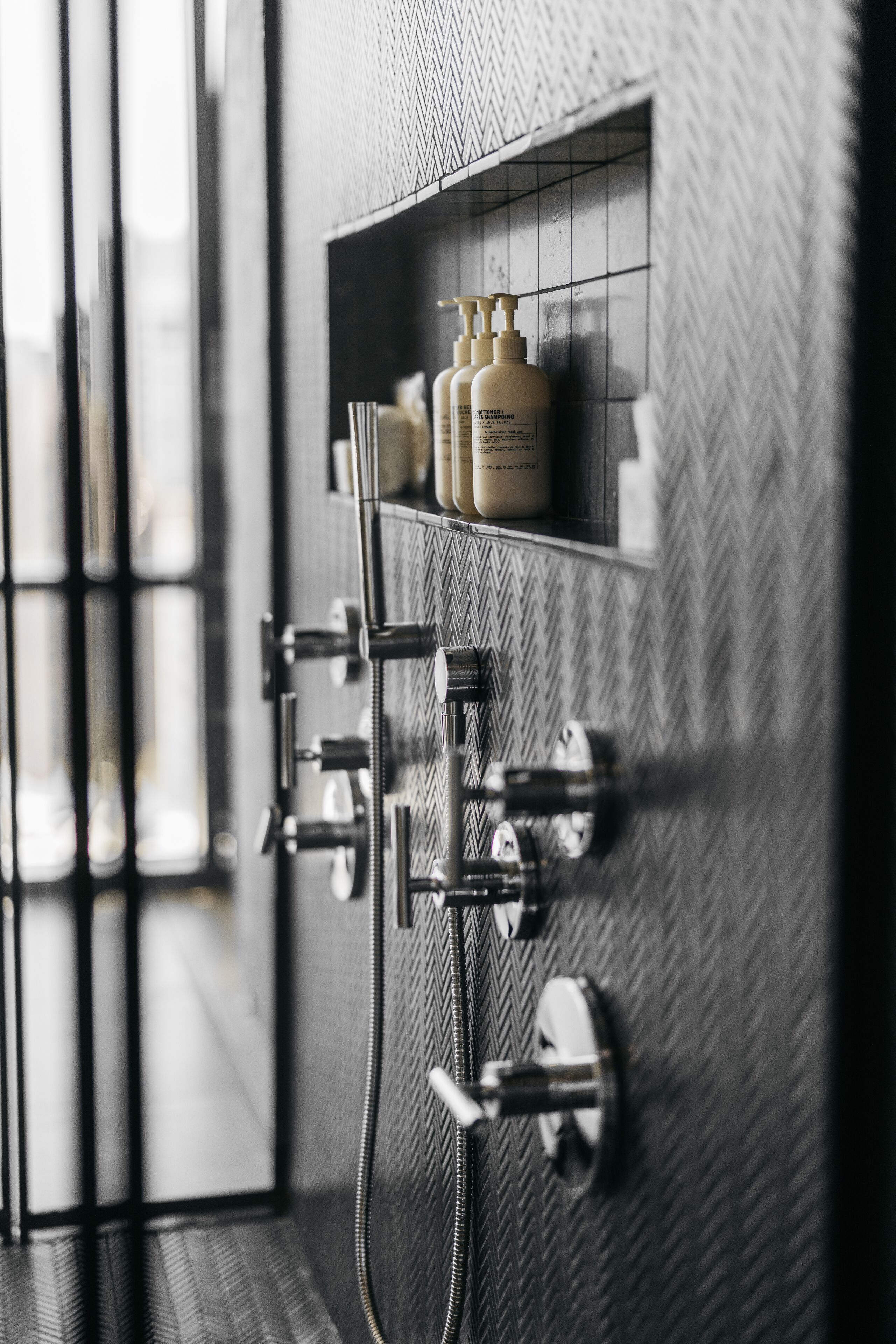 A bathroom with a shower, a towel rack, and a shelf with toiletries.