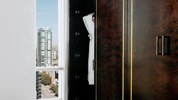 Ein modernes Interieur mit großem Kleiderschrank, einer Lederausstattung und Blick auf eine Skyline durch ein großes Fenster.