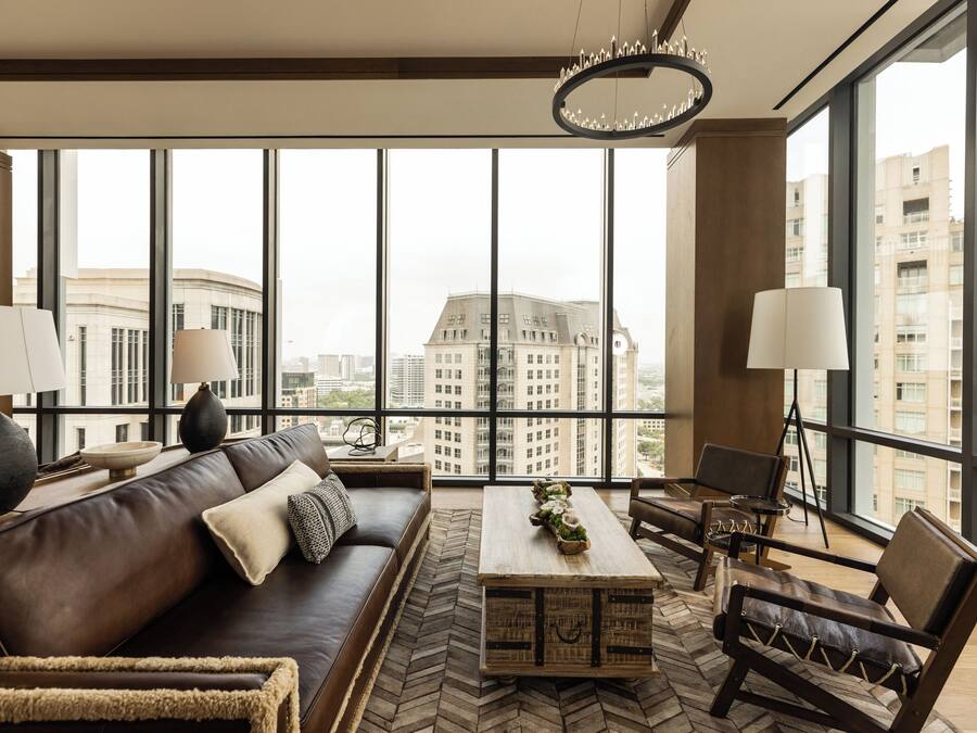 A modern living room with a large window, a sofa, a coffee table, and two chairs.