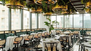 A restaurant with round tables, green booths, and hanging plants. - Hôtel Swexan (Dallas)