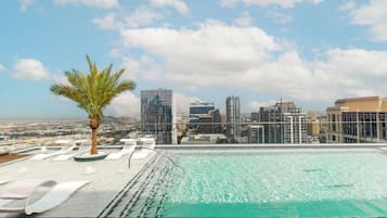 Una piscina al aire libre, sombrillas, sillones reclinables de piscina