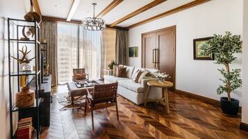 Uma sala de estar moderna com piso de madeira em padrão herringbone, um sofá, uma mesa de centro, uma cadeira de madeira, uma estante e um vaso com planta.