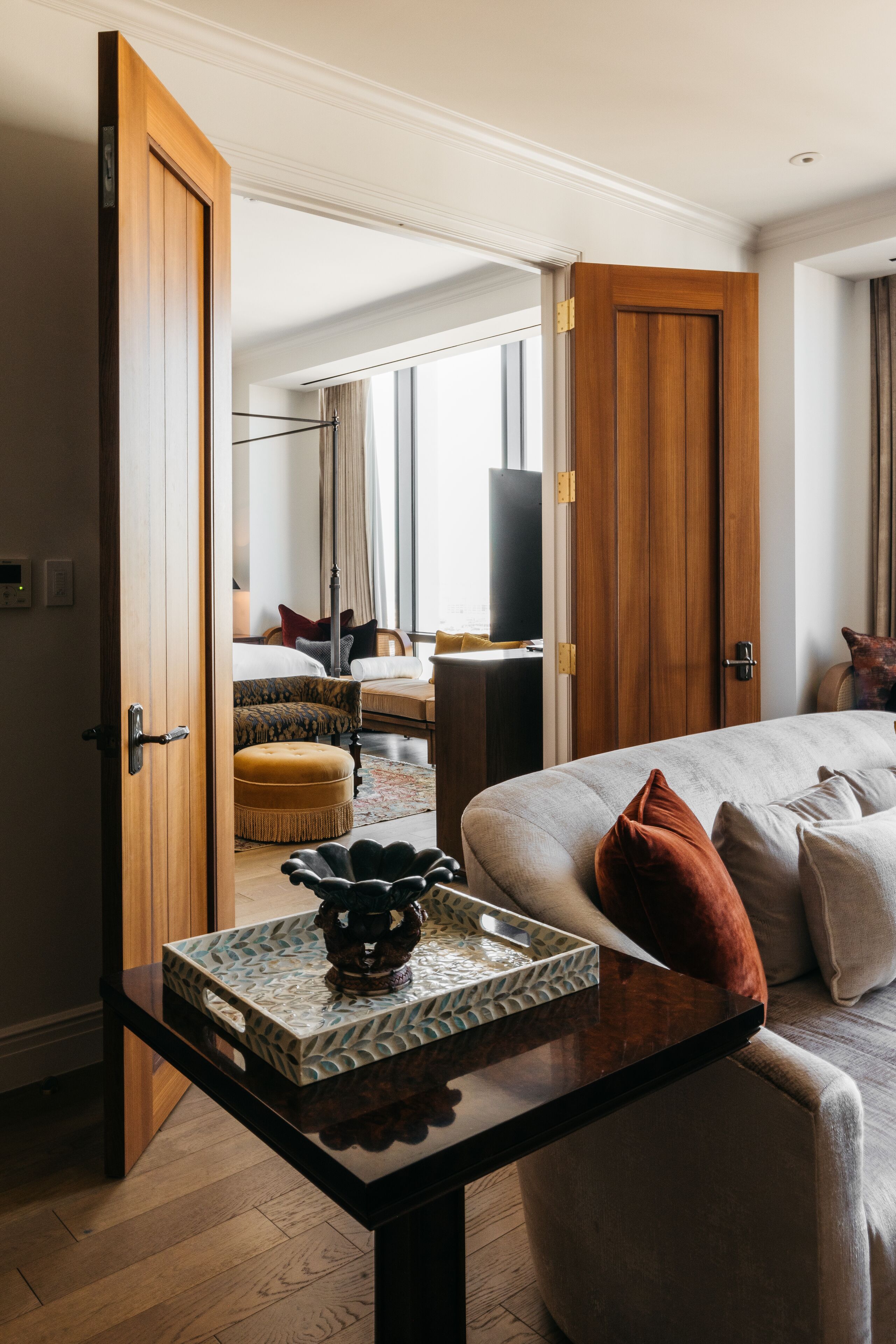 Una habitación de hotel con cama, una mesa con bandeja, una silla, un sofá, un televisor y una ventana con cortinas.