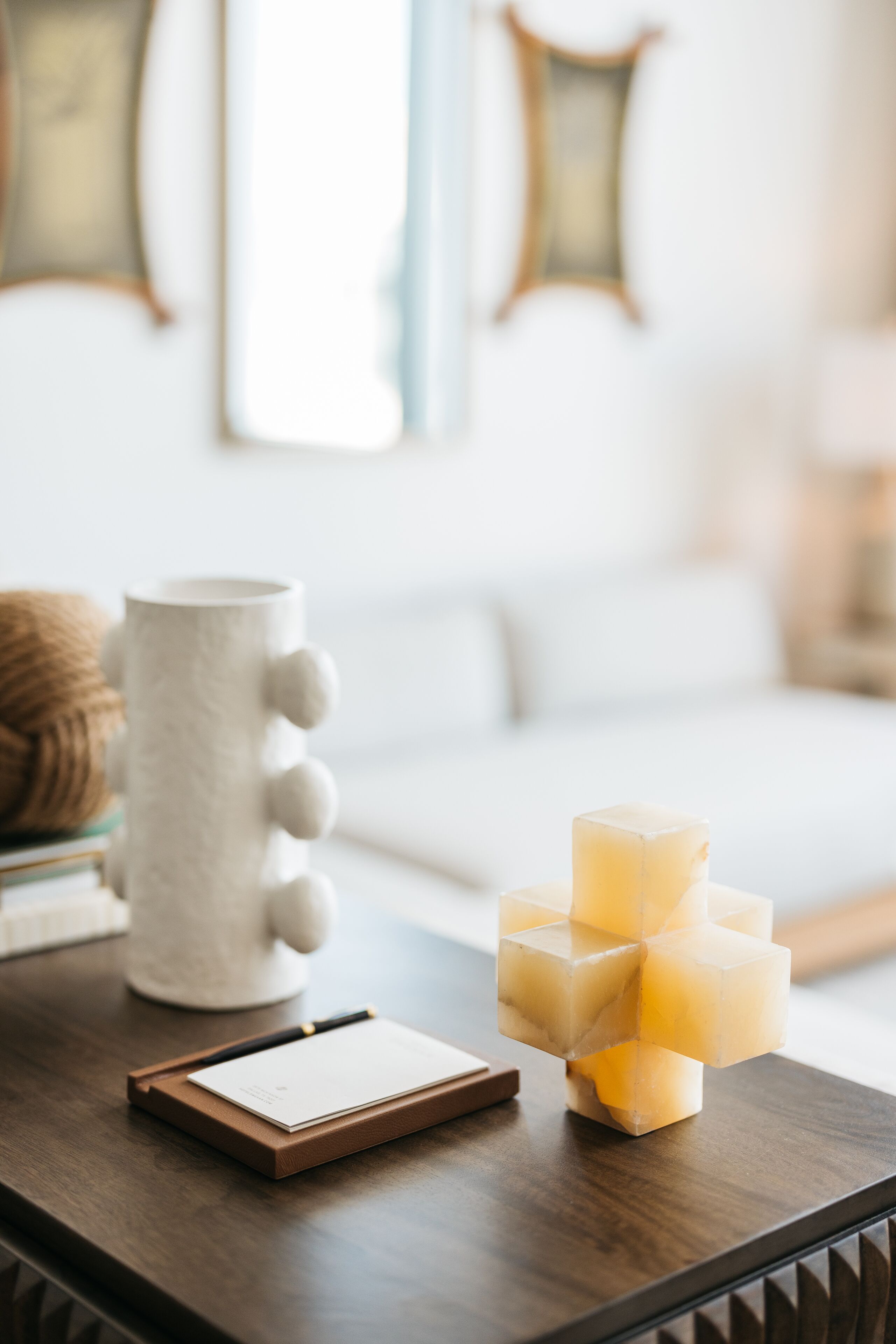 A wooden table with a notepad, a pen, and a stack of yellow cubes.