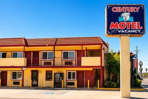 A two-story motel with a red and yellow facade, a signboard indicating no vacancy, and a parking lot with a handicapped parking space. - Century Motel Buena Park Disneyland (Buena Park)